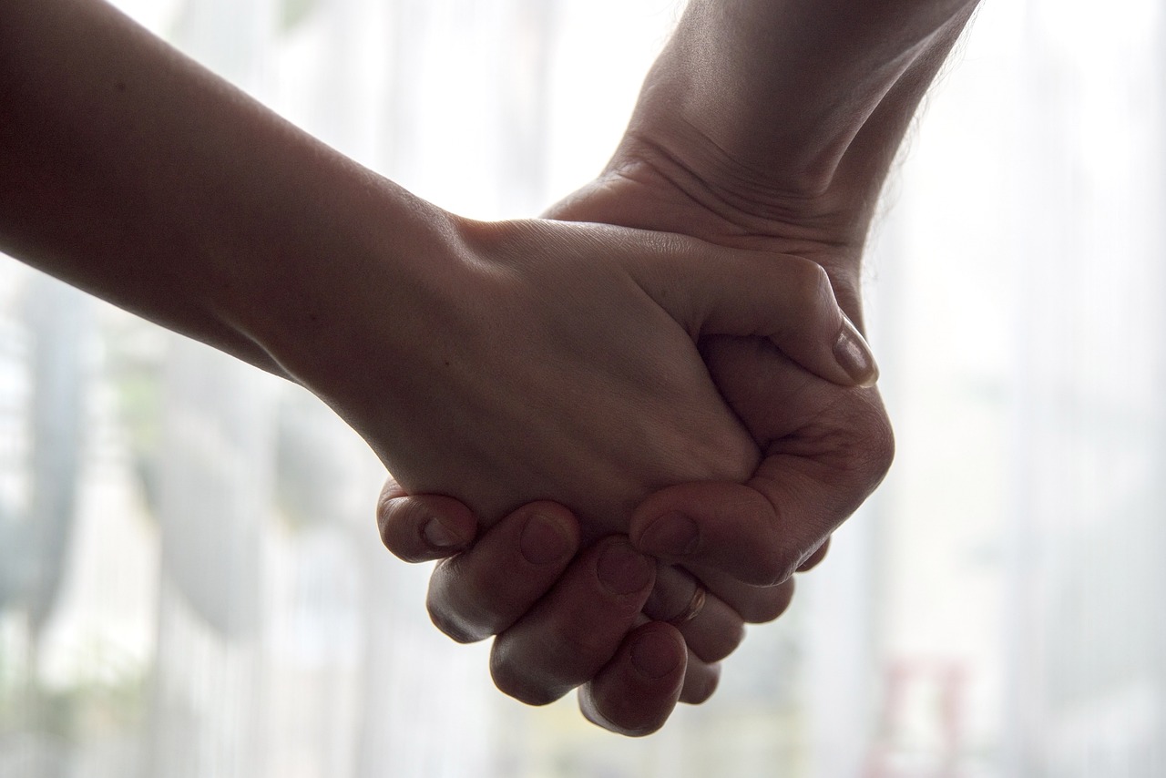 A zoomed in picture of holding hands. This is the first picture in the Birthmom Buddies blog post about why birth mothers need post-adoption support.