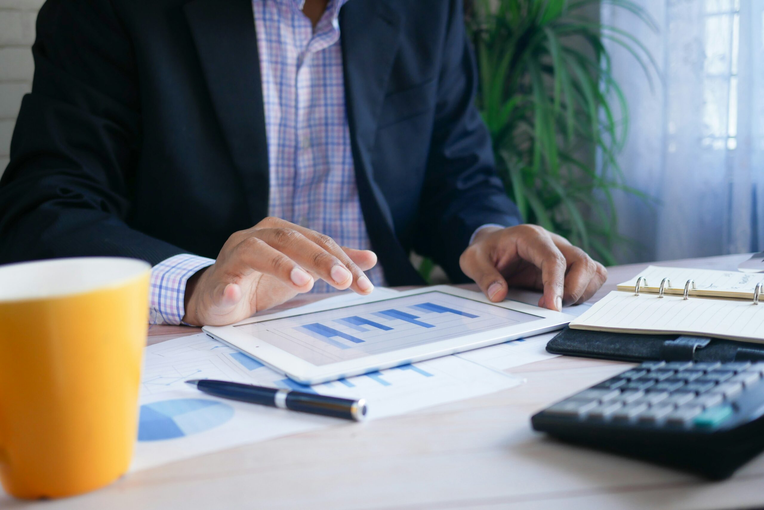 a man sitting at a desk looking at financial resources on an ipad.