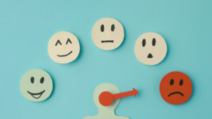 Mood scale with smiling, neutral, and sad faces, indicating shifting emotions, on a bright blue background.