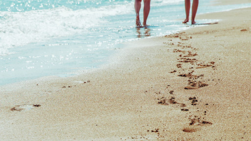 Footprints in the sand along a shoreline, representing a peaceful and reflective walk by the ocean.